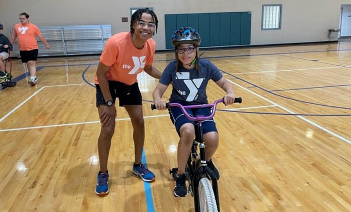 YMCA-volunteer-with-child-on-bike